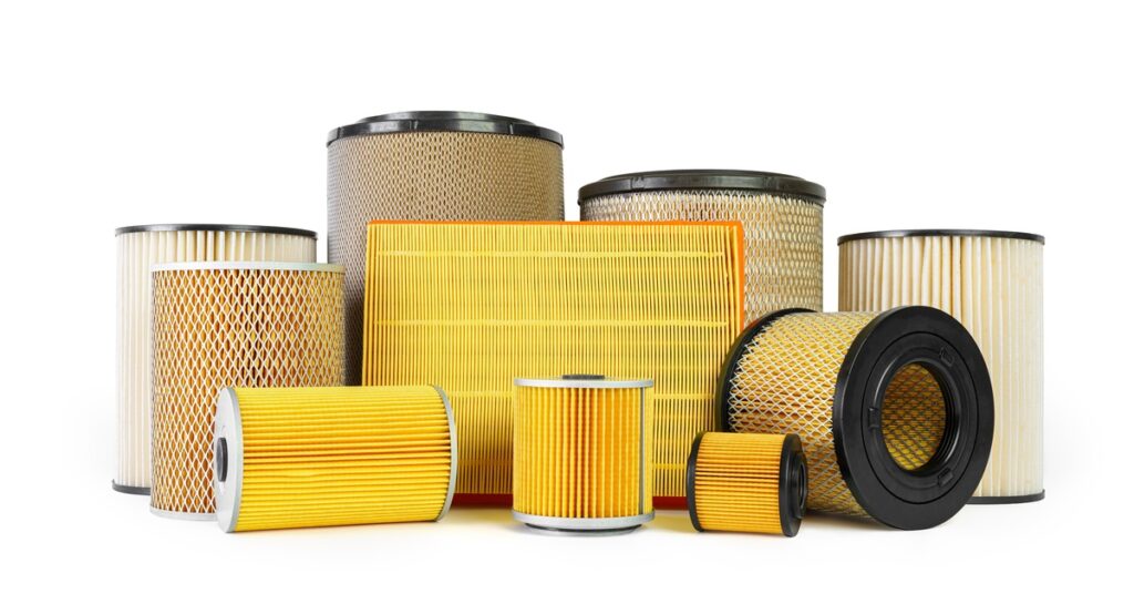A variety of yellow and tan textured cylindrical and rectangular vehicle filters on a white background.