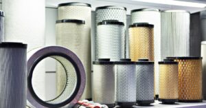 Shelves displaying cylindrical industrial air filters with pleated media, metal mesh, and rubber end caps in multiple sizes.