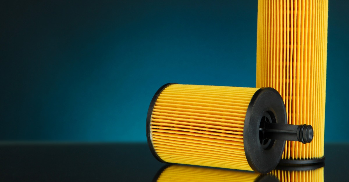 Two yellow pleated cylindrical air filters, one upright and one lying down, against a teal background.