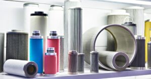 Assorted cylindrical industrial air filters in various sizes and colors displayed on white shelving units.