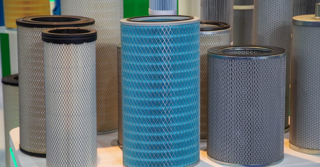 Multiple cylindrical industrial air filters with mesh exteriors displayed upright on a white surface.