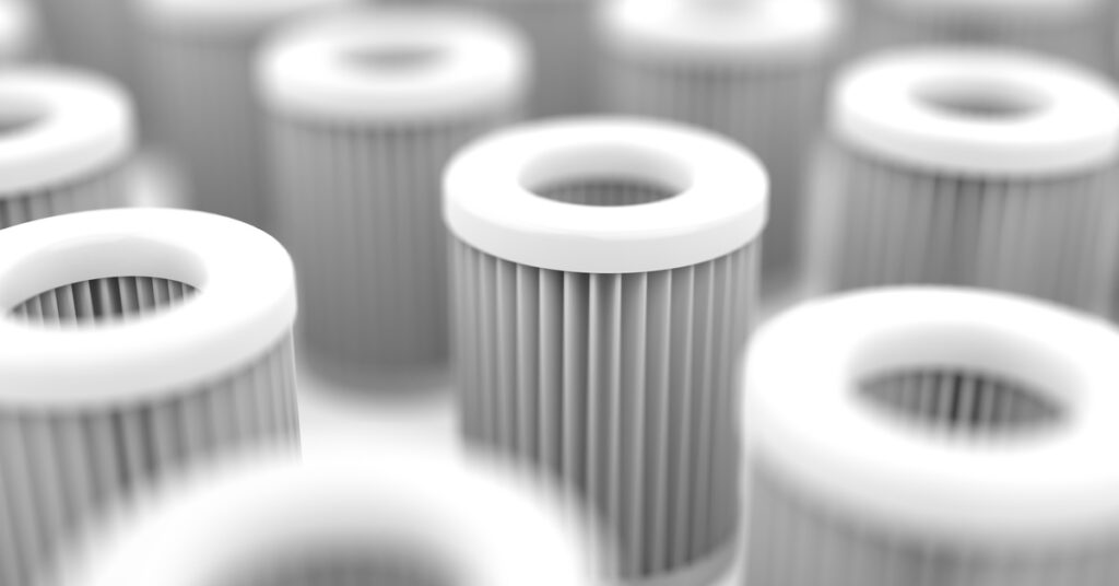 A close-up of multiple white cylindrical air filters with pleated sides, arranged in rows with a shallow depth of field.
